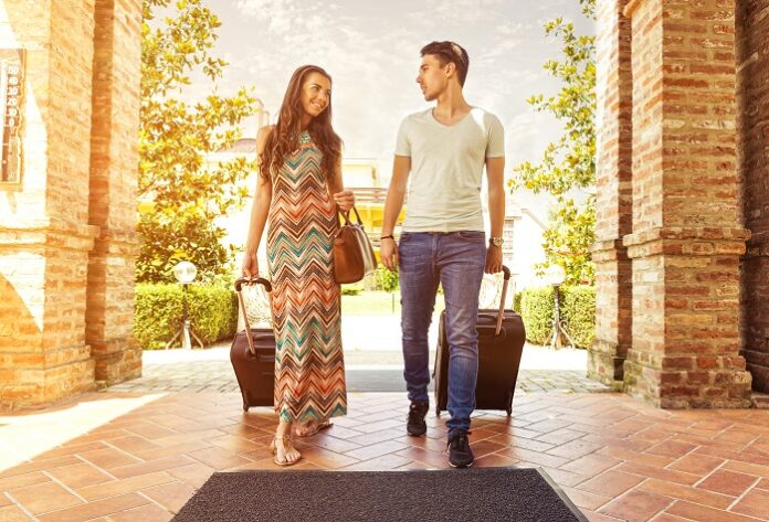 Young couple standing at hotel corridor upon arrival, looking for room, holding suitcases Mayıs Ayında Türkiye’de Gezilecek Yerler