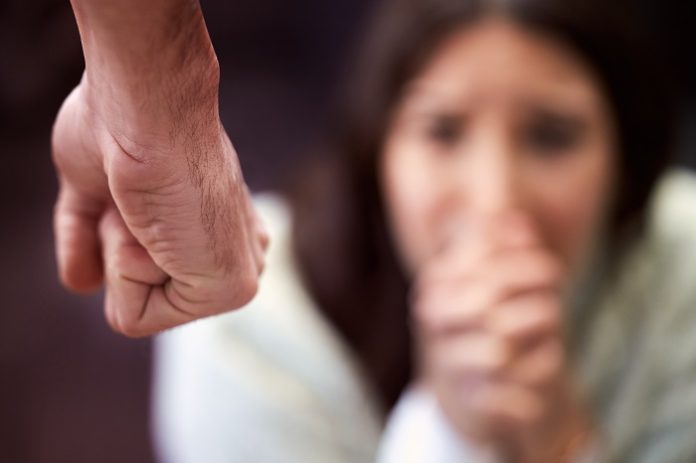 Violence solves nothing. a mans fist with a woman looking scared in the background.